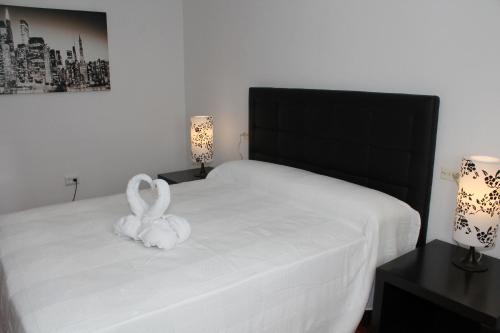 a white bunny sitting on a white bed with two lamps at Can Mossènyer in San Antonio