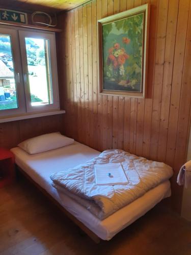 a small bed in a room with two windows at Lake Lodge Hostel in Iseltwald