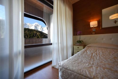 a bedroom with a bed and a window with a mountain view at Hotel Corona in Val di Zoldo