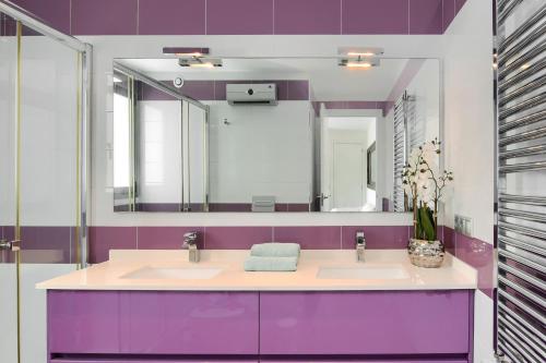 een paarse badkamer met 2 wastafels en een spiegel bij Graham Holiday Rentals - Baladrar in Benissa