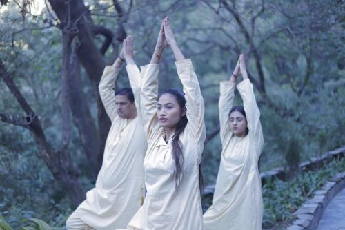 a group of people in white doing yoga at Yog Wellness Resort & Spa By Amritara in Mussoorie