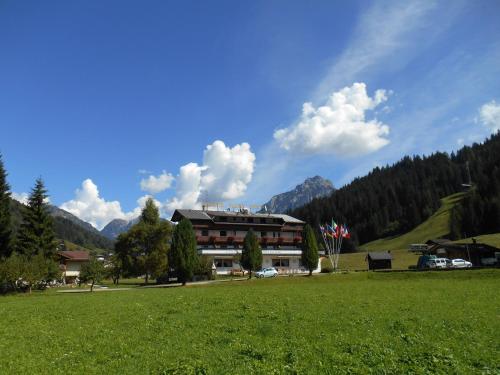a building in the middle of a green field at Monaco Sport Hotel in Santo Stefano di Cadore