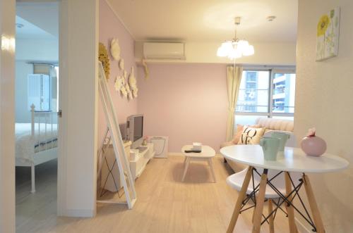 una pequeña sala de estar con una mesa y una cama en River Side Namba 603, en Osaka