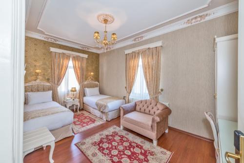 a bedroom with two beds and a chair and a chandelier at Enderun Hotel Istanbul in Istanbul