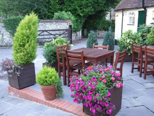 a patio with a table and chairs and flowers at Ye Olde George Inn - Badger Pubs in Privett
