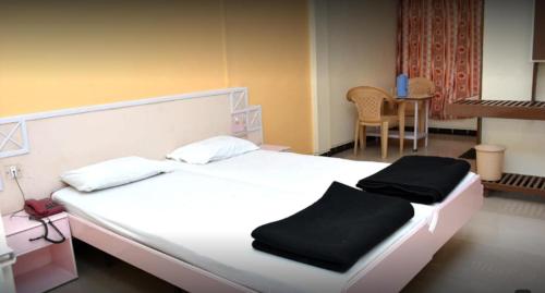 a bedroom with a white bed with black towels on it at Hotel Rajesh in Kolhapur