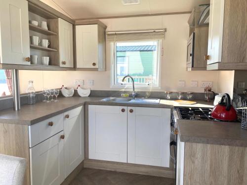 a kitchen with white cabinets and a sink at 37 Bay View Oceans Edge by Waterside Holiday Lodges in Lancaster