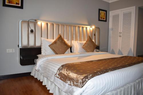 a bedroom with a large bed with white sheets and pillows at Ramada Plaza by Wyndham Karachi Airport Hotel in Karachi
