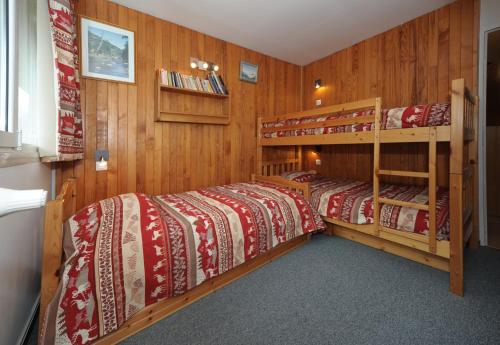 deux lits dans une chambre aux murs en bois dans l'établissement travelski home select - Résidence les Lauzes, aux Menuires