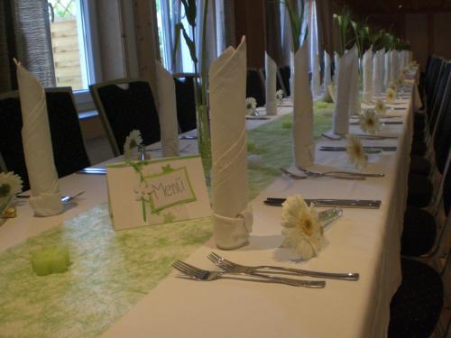 een lange tafel met borden, vorken en bloemen erop bij Landhotel Löwen in Blumberg