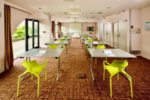 une salle de classe avec rangées de tables et de chaises jaunes dans l'établissement Holiday Inn Lyon Vaise, an IHG Hotel, à Tassin-la-Demi-Lune