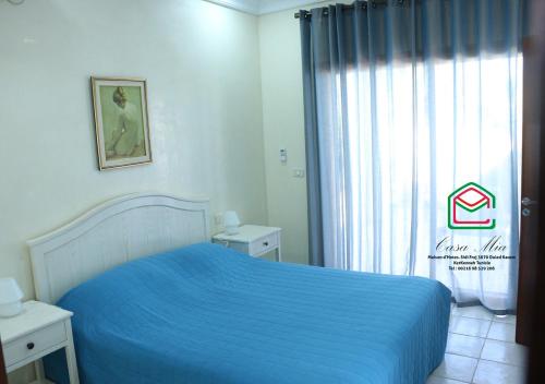 a bedroom with a blue bed and a window at Casa Mia in Ouled Kacem