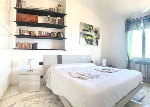sypialnia z białym łóżkiem i półką na książki w obiekcie La Casa sui Tetti w Genui