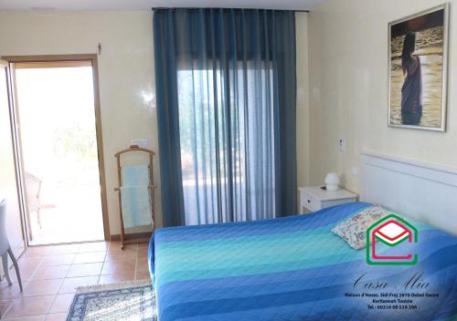 a bedroom with a blue bed and a large window at Casa Mia in Ouled Kacem
