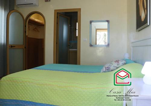 a bedroom with a bed with a green blanket at Casa Mia in Ouled Kacem