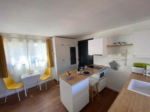 une cuisine avec des armoires blanches et des chaises jaunes dans l'établissement Les cèdres, à Uzès