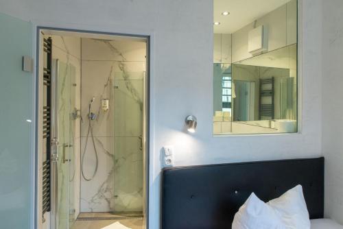 a bathroom with a shower and a bed and a mirror at Hotel Fischertor in Augsburg