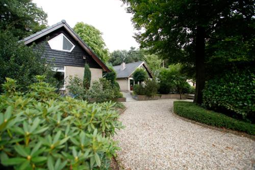 uma casa com uma entrada de cascalho em frente a uma casa em Vakantie bij Meeussen - Schuttersoord em Mook