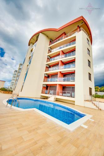 a building with a swimming pool in front of it at Sveti Luka Apartments in Dobra Voda