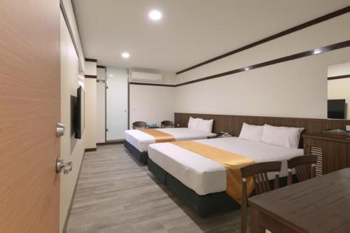 ein Hotelzimmer mit 2 Betten und einem Tisch in der Unterkunft Royal Holiday Imv in Stadtteil Baihe District