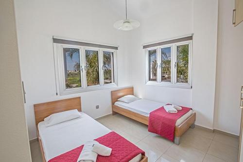 1 dormitorio con 2 camas y 2 ventanas en Villa Adaman - Stunning 3 Bedroom Seafront Villa with Pool - Close to the Beach, en Ayia Napa