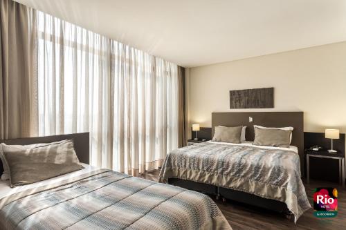 a bedroom with two beds and a large window at Rio Hotel by Bourbon Curitiba Aeroporto in São José dos Pinhais