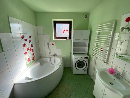 a bathroom with a tub and a sink and a washing machine at Dom do wynajęcia "Zawojski Zakątek" in Zawoja