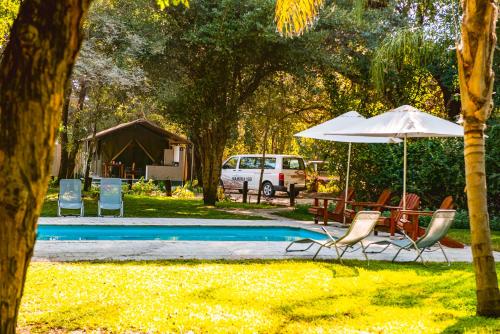 - un groupe de chaises et un parasol à côté de la piscine dans l'établissement Zambezi Mubala Campsite, à Katima Mulilo