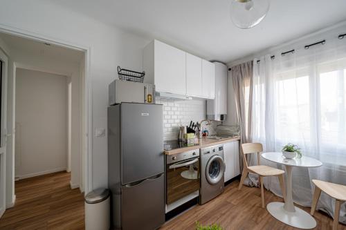 a small kitchen with a refrigerator and a table at Le Petit Drancy - T2 tout équipé in Drancy