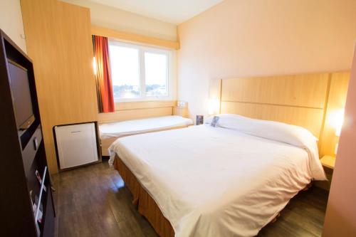 a bedroom with a large white bed and a window at ibis Presidente Prudente Manoel Goulart in Presidente Prudente