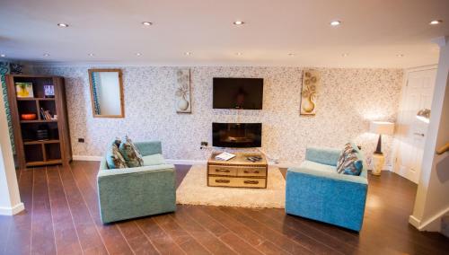 a living room with two couches and a tv at Albion Guest House & Apartments in Pembroke Dock