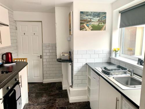 cocina blanca con fregadero y ventana en Milburn Cottage 2- Luxury Accommodation en Monkwearmouth