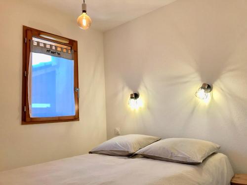 a bedroom with a bed with two pillows and a window at Appartement 8 personnes à 3 minutes des pistes in Le Dévoluy