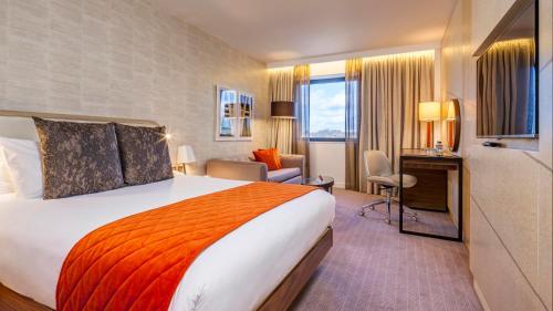 Cette chambre comprend un grand lit et un bureau. dans l'établissement Crowne Plaza London Kings Cross, an IHG Hotel, à Londres
