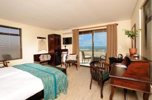 a hotel room with a bed and a desk and a balcony at Beach Hotel Swakopmund in Swakopmund