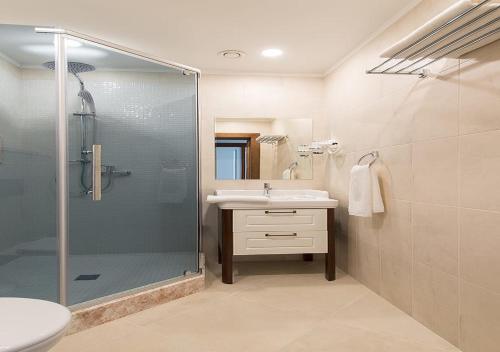 a bathroom with a glass shower and a sink at Boutique Hotel Kaspi in Temirtaū