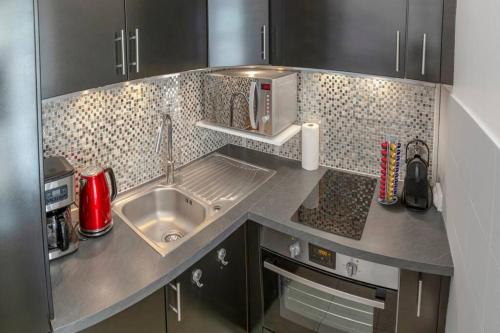 a small kitchen with a sink and a microwave at Logement de charme - Porto Riche - Cœur historique Bordeaux in Bordeaux
