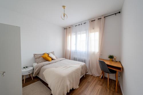 een slaapkamer met een bed, een bureau en een raam bij Le Petit Drancy - T2 tout équipé in Drancy
