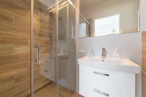 uma casa de banho com um lavatório e um chuveiro em Marina Domki Apartamentowe em Jastarnia