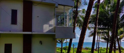 a building with a balcony with a view of the ocean at White Shell Beach House in Kannur