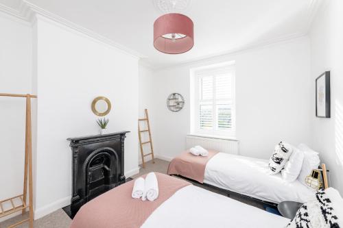 two beds in a room with a fireplace at Modern & Spacious 2 Bedroom Maisonette in Bath