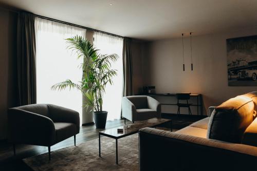 a living room with a couch and chairs and a plant at Hotel Sanglier in Durbuy