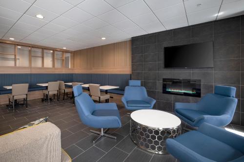 a waiting room with blue chairs and tables and a tv at Microtel Inn & Suites by Wyndham Loveland in Loveland
