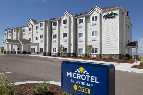 a hotel with a sign in front of a building at Microtel Inn & Suites by Wyndham Loveland in Loveland