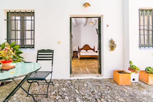 um pátio com uma mesa, cadeiras e uma cama em Cortijo El Indiviso em Vejer de la Frontera