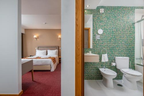 レイリアにあるHotel Sao Luisのベッドとバスルーム付きのホテルルームです。