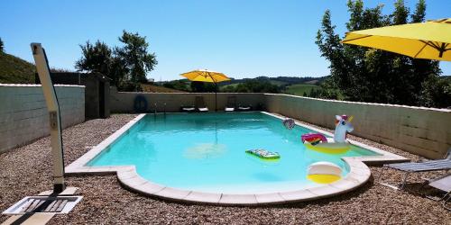 - une petite piscine avec un parasol et des chaises dans l'établissement La Tranquillité, Le Calme, à Nanteuil-Auriac-de-Bourzac
