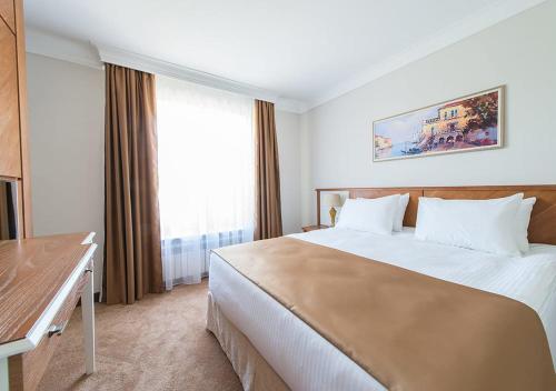 a hotel room with a large bed and a window at Boutique Hotel Kaspi in Temirtaū