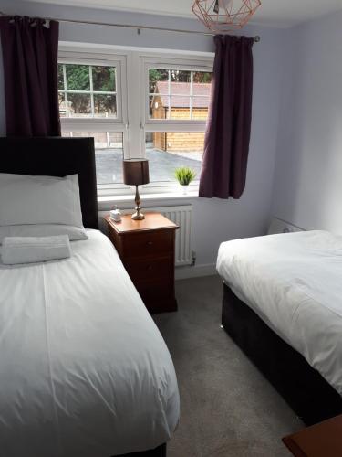 - une chambre avec 2 lits et une fenêtre dans l'établissement RentUnique St Georges 2x 2 bed amazing apartments moments from centre, à Horley