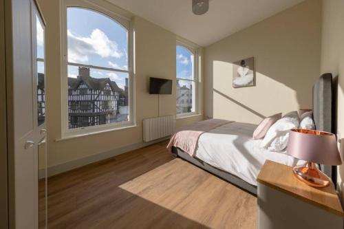 a bedroom with a bed and two large windows at Apartment 1 Isabella House, Aparthotel, By RentMyHouse in Hereford